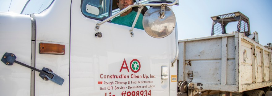 Antonio Ornelal driving his roll-off dumpster truck to his next rental for junk removal.